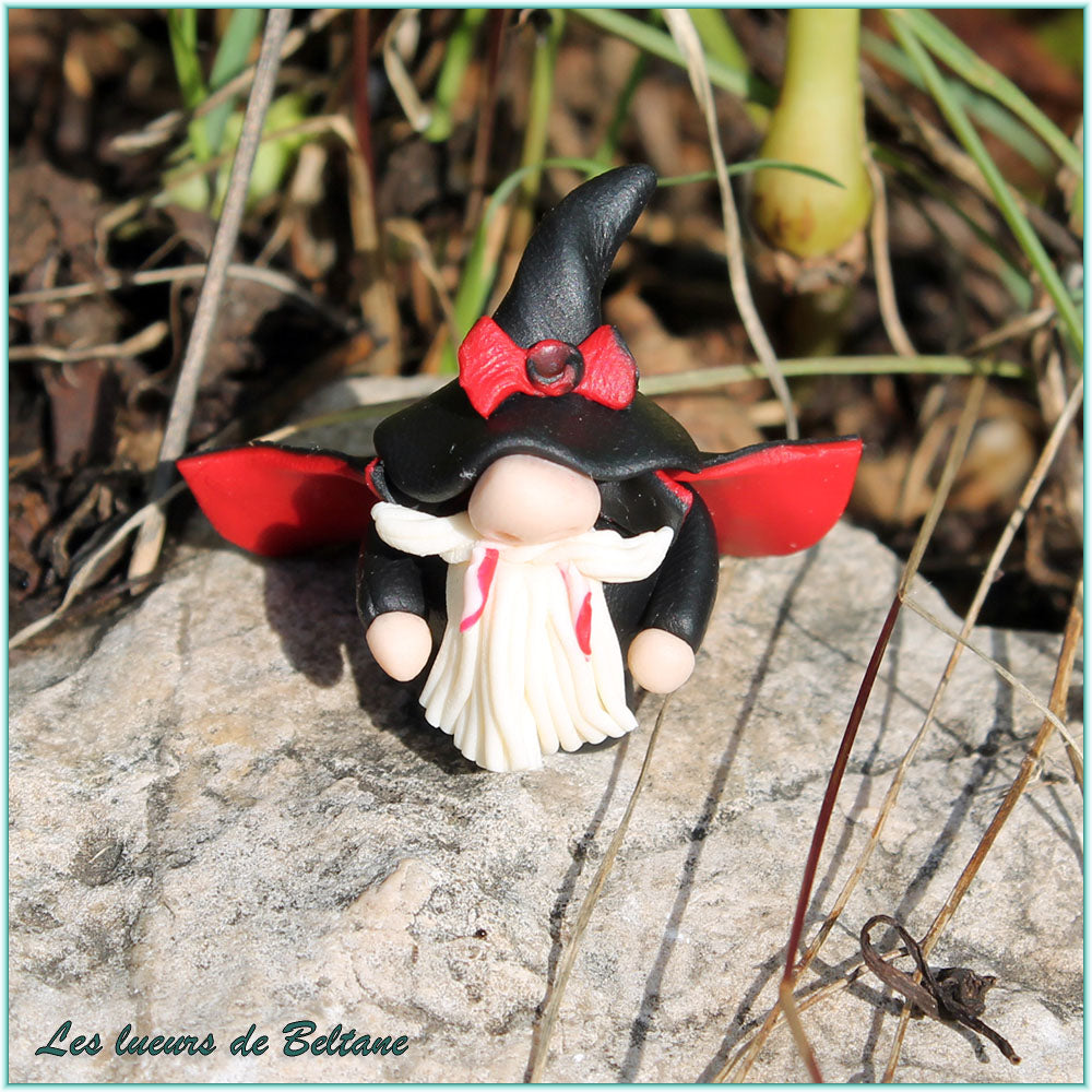 Abhartach, gnome vampire au chapeau noir et nœud rouge, posé sur une pierre