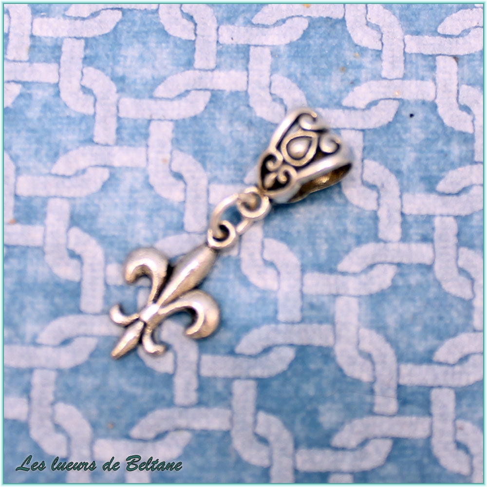 Pendentif fleur de lys en métal argenté sous une large bélière à volutes
